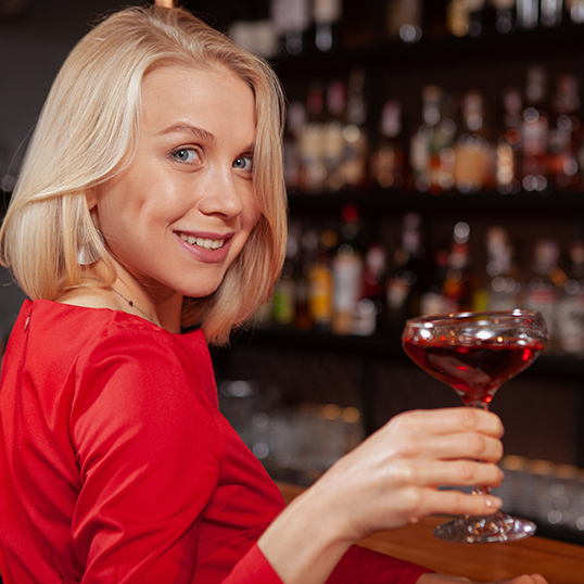 A bartender pouring a signature cocktail across a dimly lit bar.